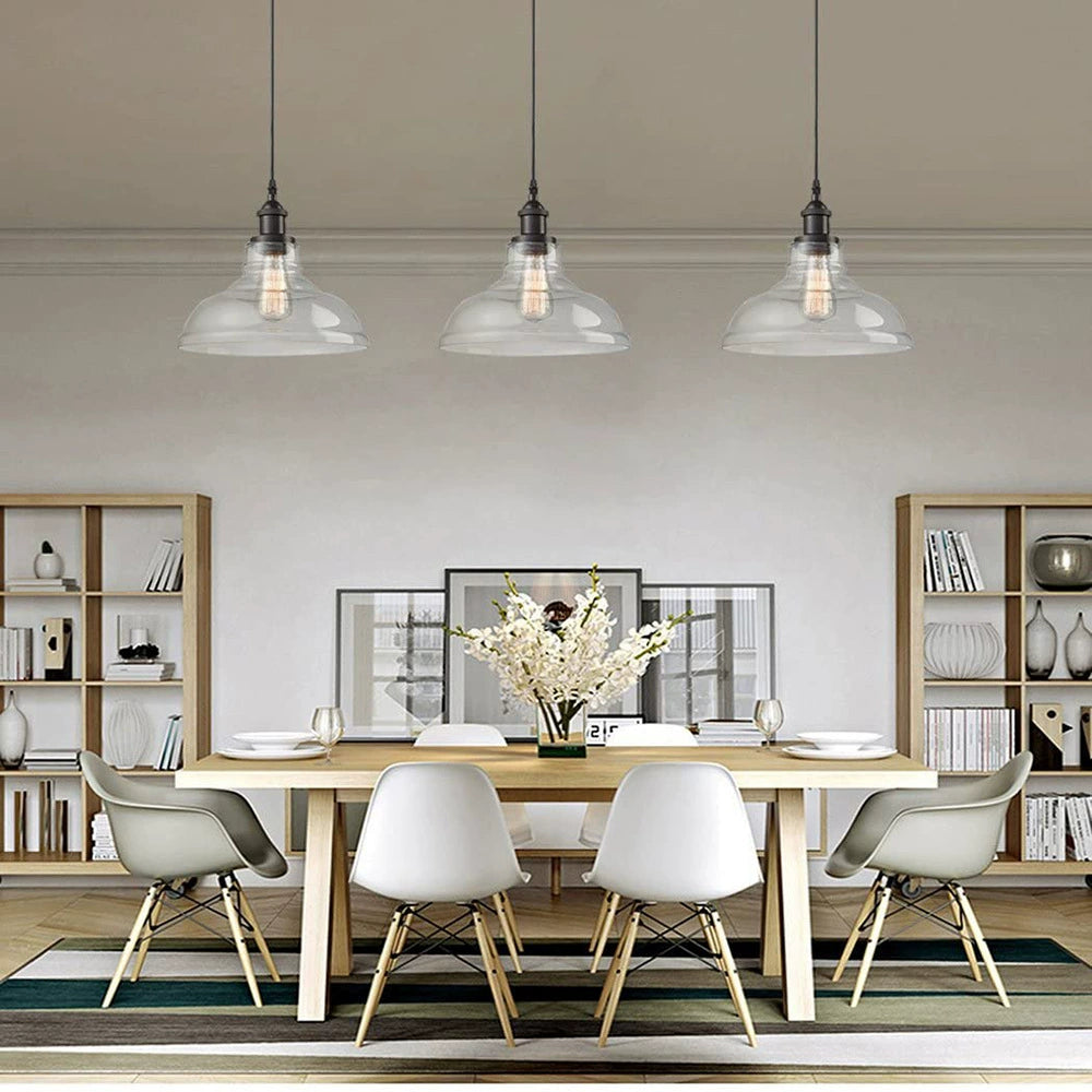 Clear bell glass pendant lights above a dining table; each pendant sold individually